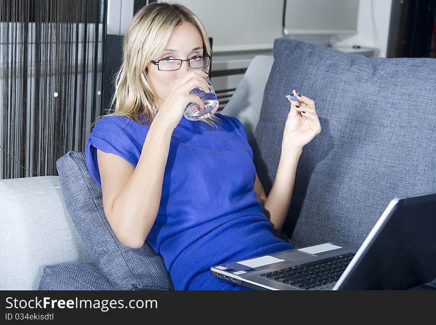 Blond woman taking a pill with a glass of water