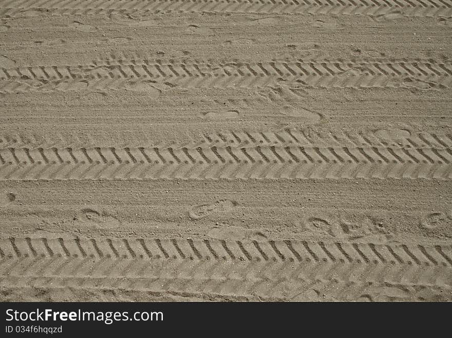 Footprints and tyre tracks in sand