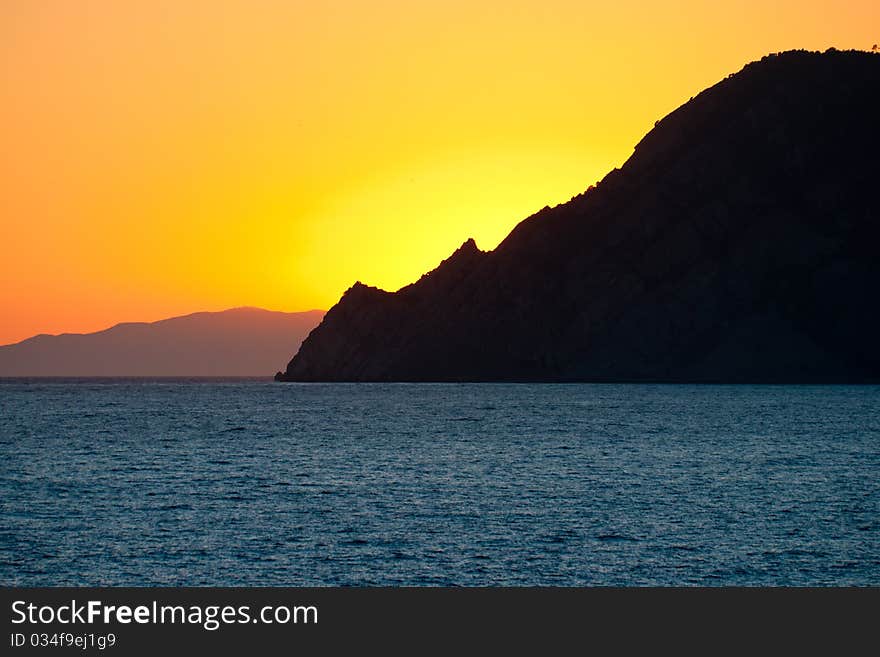 Beatifyl orange sunset over the blue sea behind the mountain. Beatifyl orange sunset over the blue sea behind the mountain