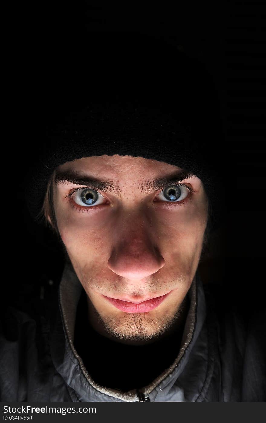 Young white Caucasian male wears a black beanie surrounded by a black copyspace background. Young white Caucasian male wears a black beanie surrounded by a black copyspace background.