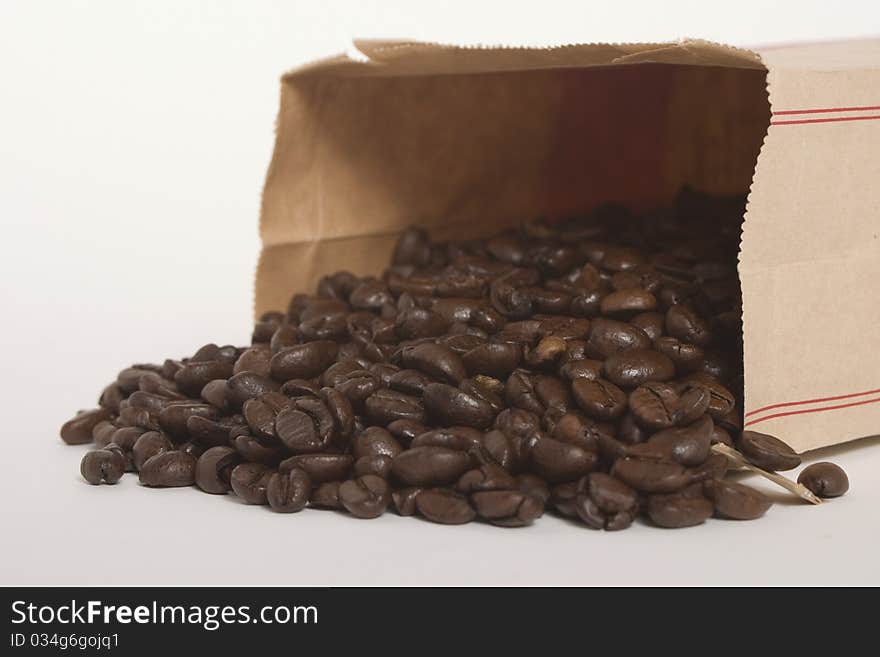 Multiple, brown coffee beans in a brown paper bag