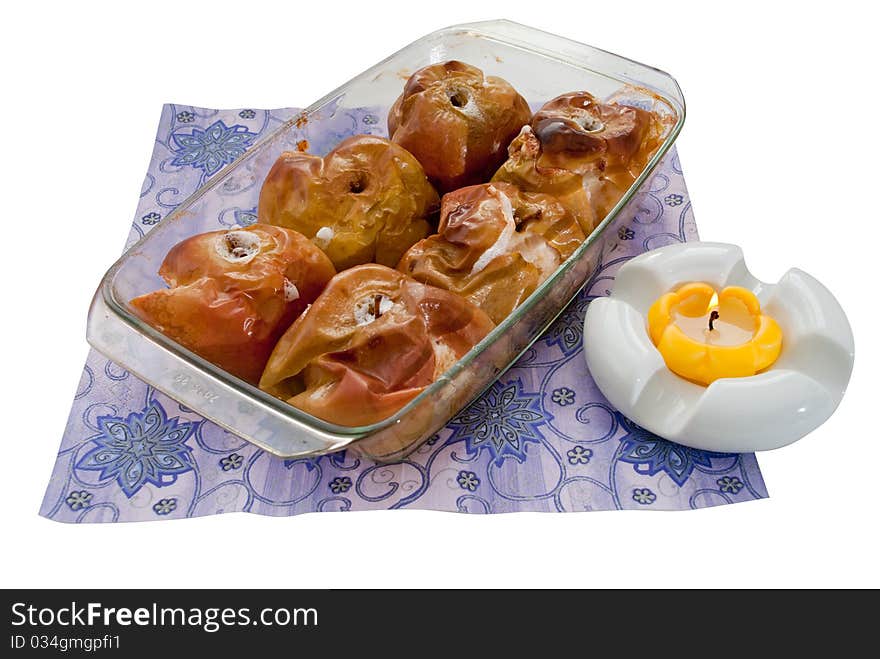 Many apples freshly baked and a lit yellow candle, everything on a white background. Many apples freshly baked and a lit yellow candle, everything on a white background