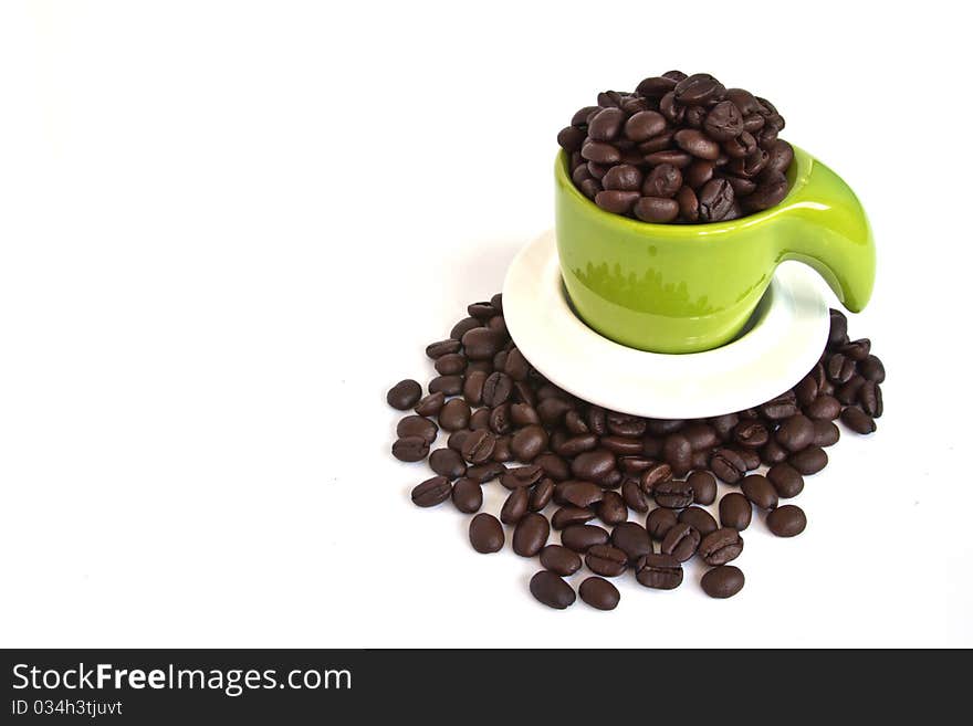 Coffee beans in green cup on white background