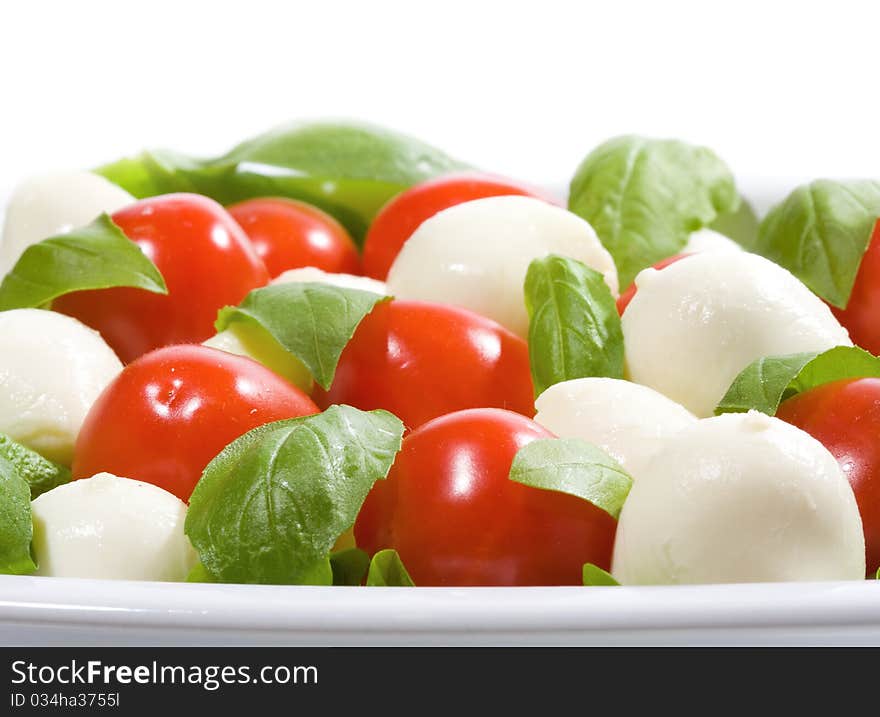 Salad with mozzarella and tomatoes on white background