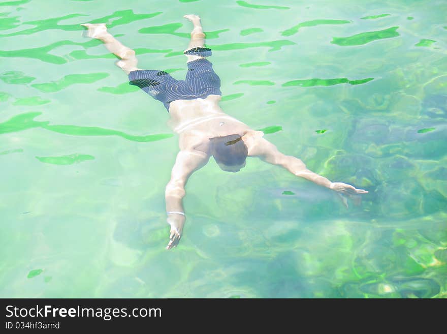 A young, muscular man swimming underwater. A young, muscular man swimming underwater