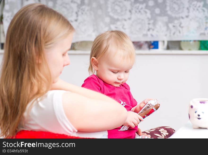 Young mother eat chocolate with adorable daughter in kitchen