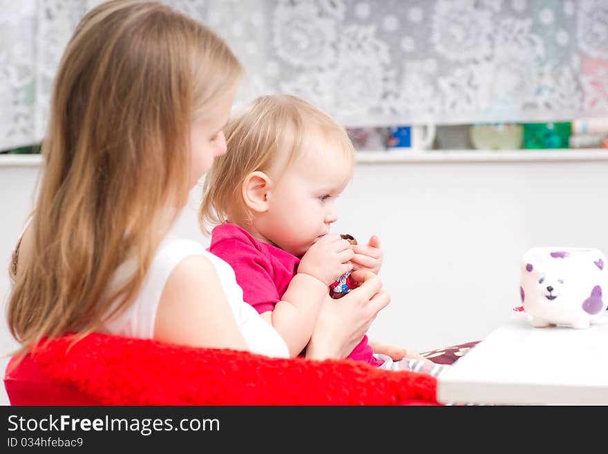 Young mother eat chocolate with adorable daughter in kitchen