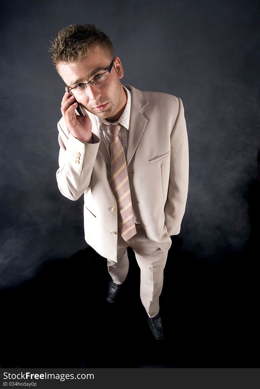 Elegant man standing on a black background. Businessman talking on the phone