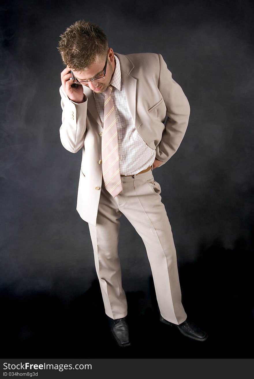 Elegant man standing on a black background. Businessman talking on the phone