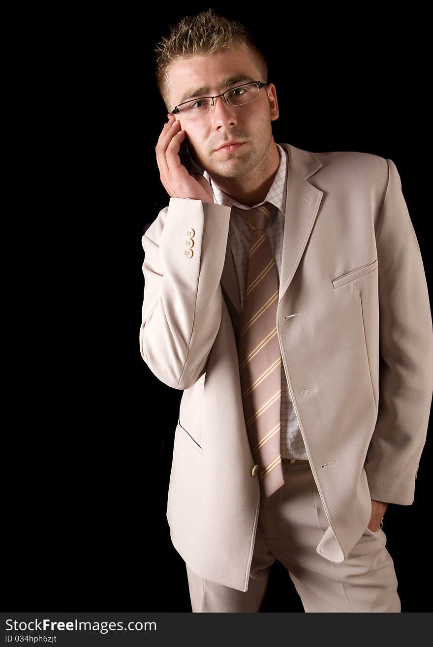 Elegant man standing on a black background. Businessman talking on the phone