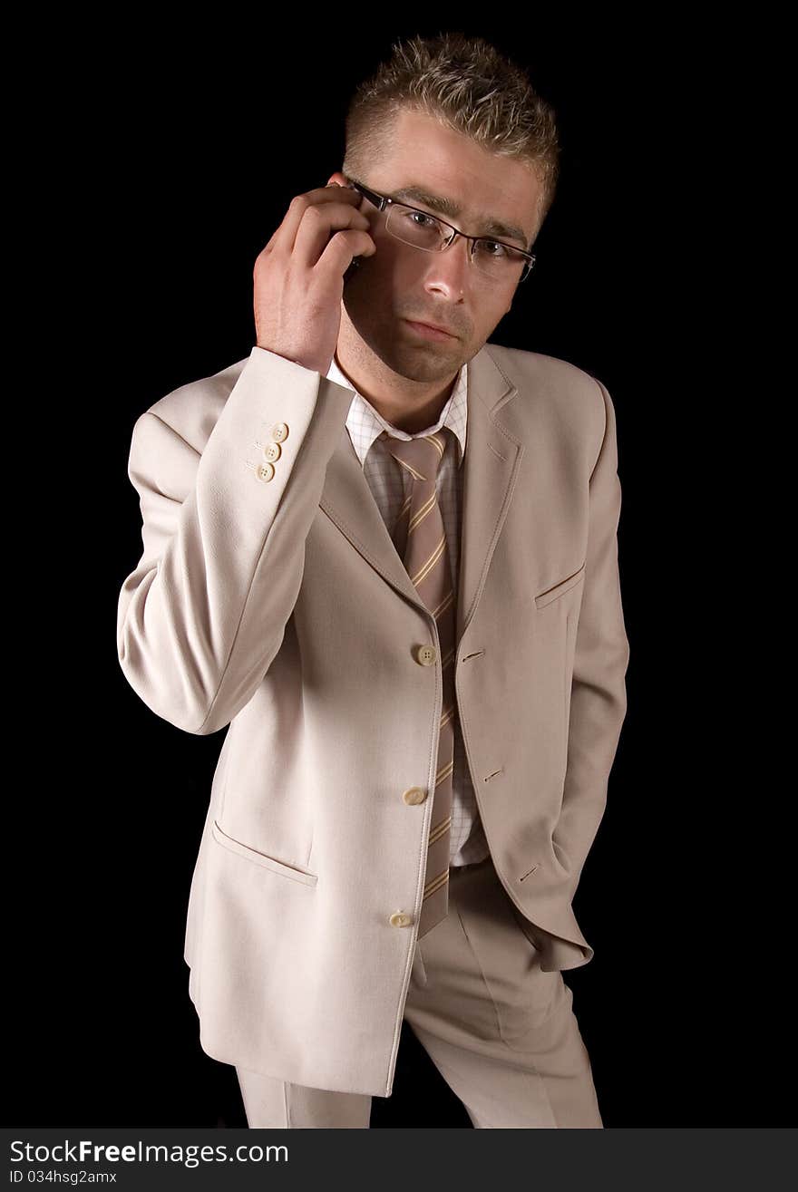 Elegant man standing on a black background. Businessman talking on the phone