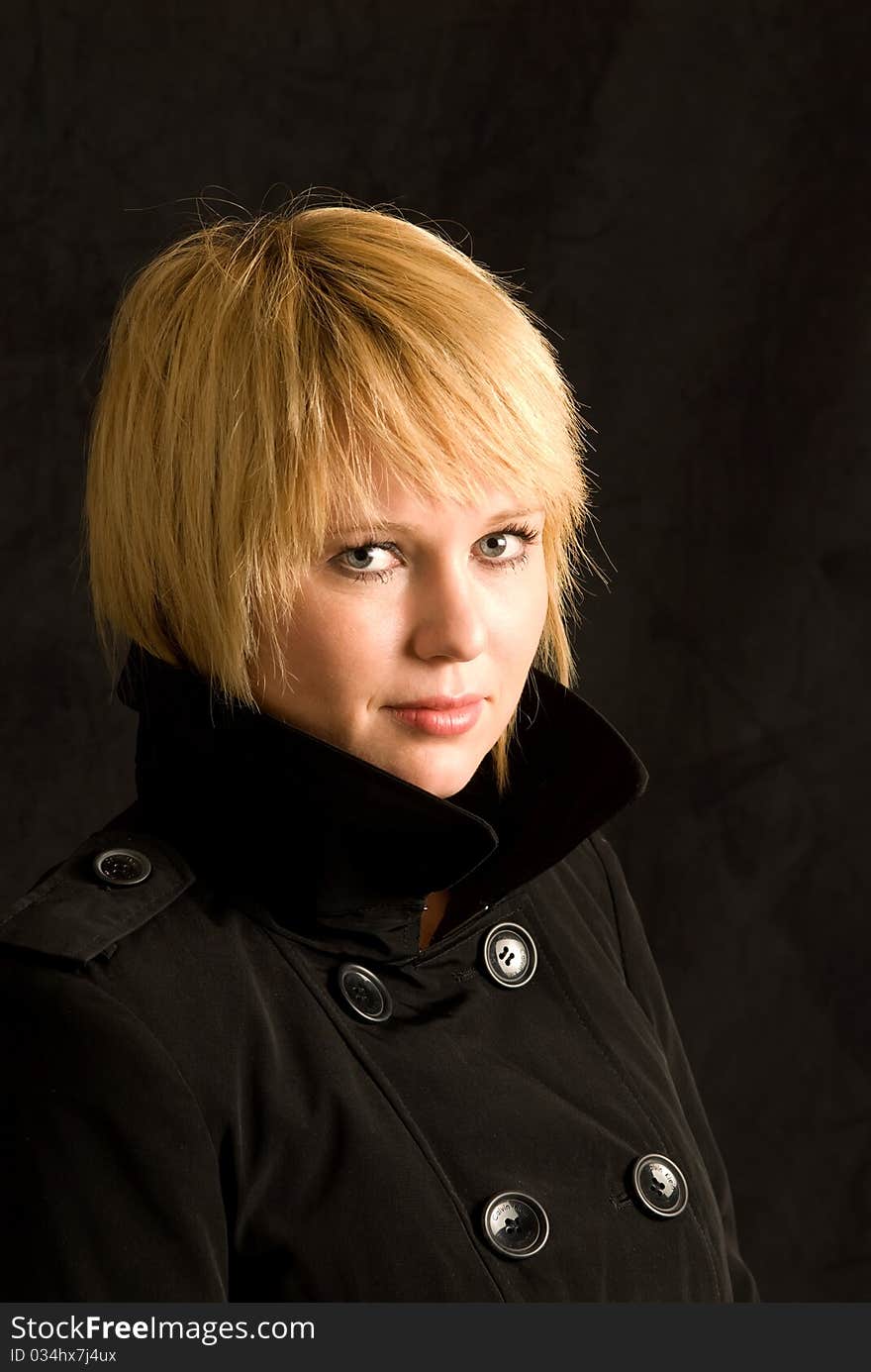 Blond woman in black trench coat.