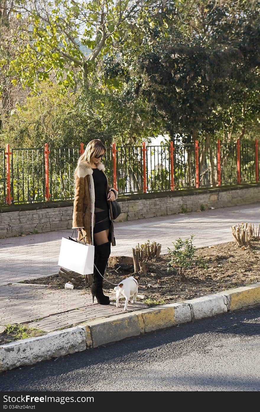 Blond woman walking down the fashion district of a modern city with a jack russel. Blond woman walking down the fashion district of a modern city with a jack russel