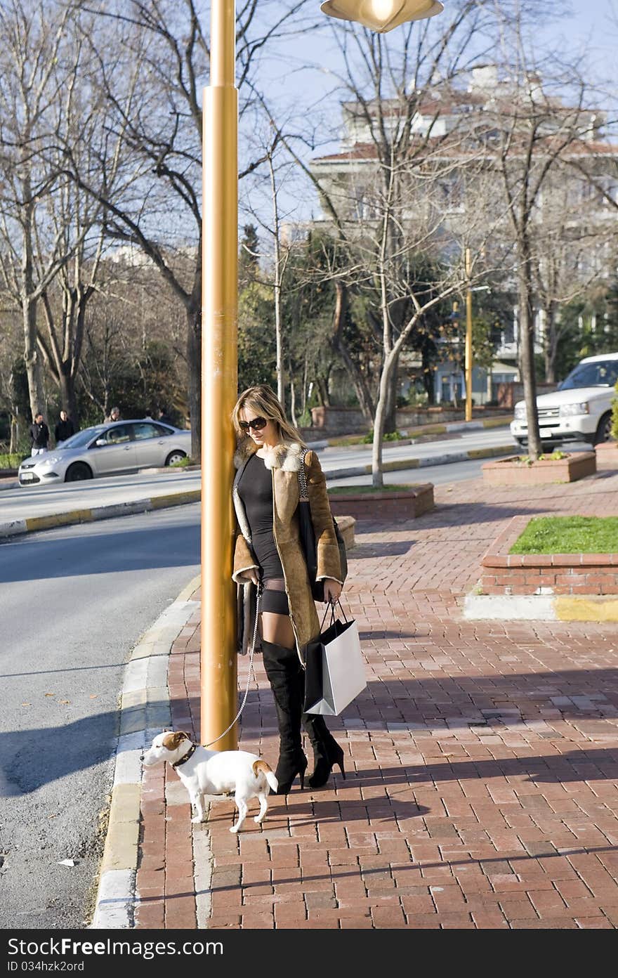 Blond woman walking down the fashion district of a modern city with a jack russel. Blond woman walking down the fashion district of a modern city with a jack russel