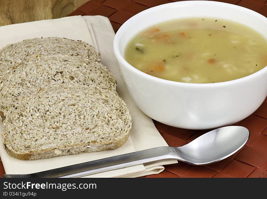 A bowl of healthy chicken soup and whole grain bread. A bowl of healthy chicken soup and whole grain bread