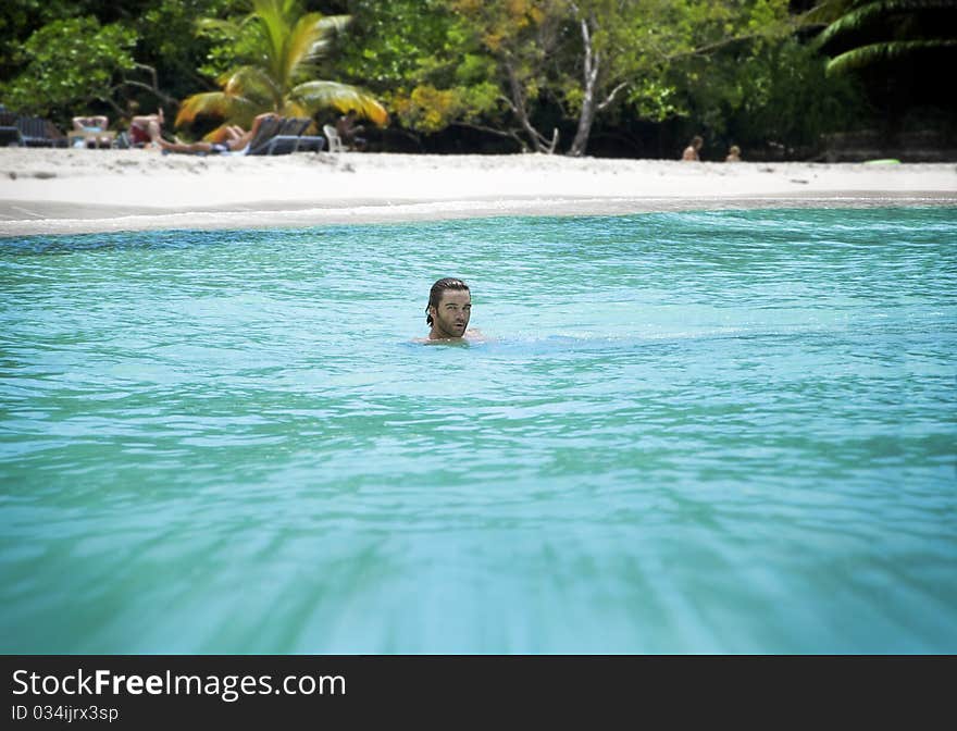 Scenic photo of a young man on vacation in beautiful chrystal clear tropical waters with shallow depth of field