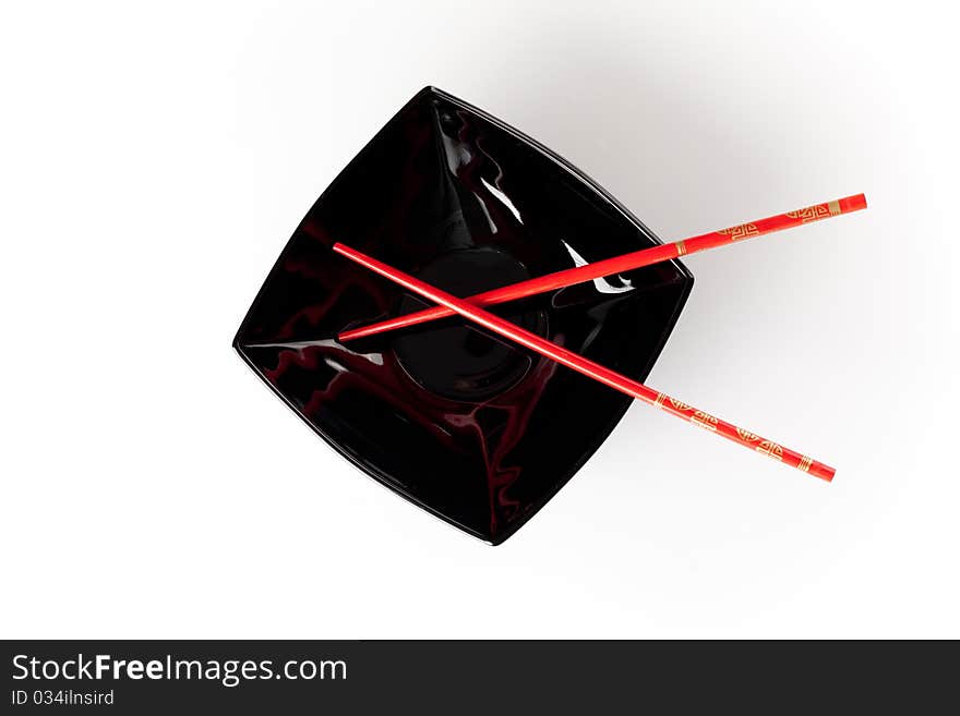 Black plate with red chopsticks isolated