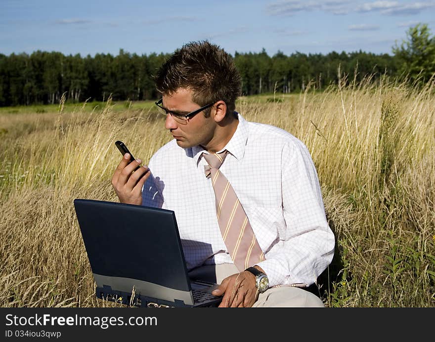 Elegant businessman working on his laptop in nature.