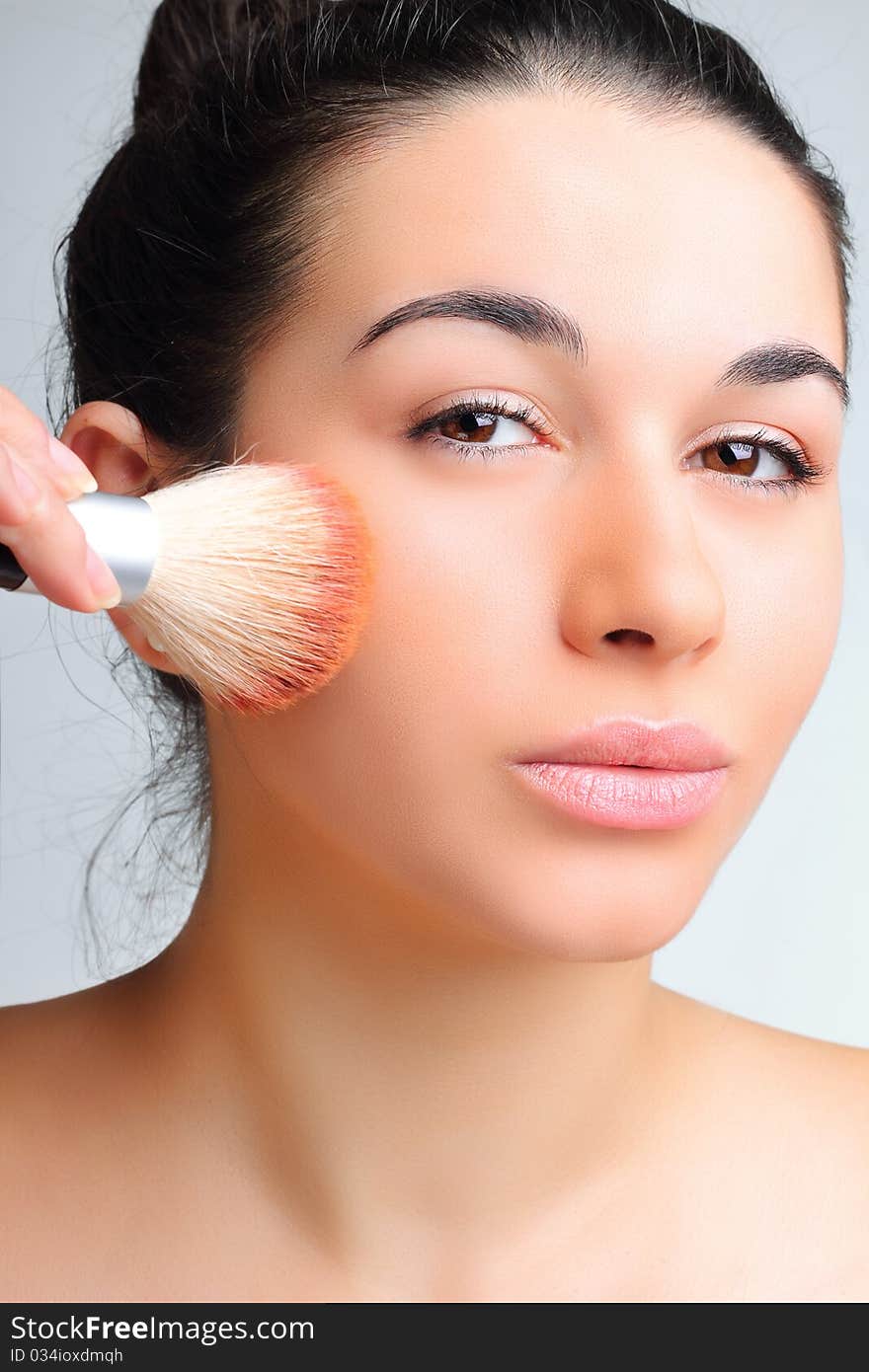 Beautiful woman applying make-up with brush