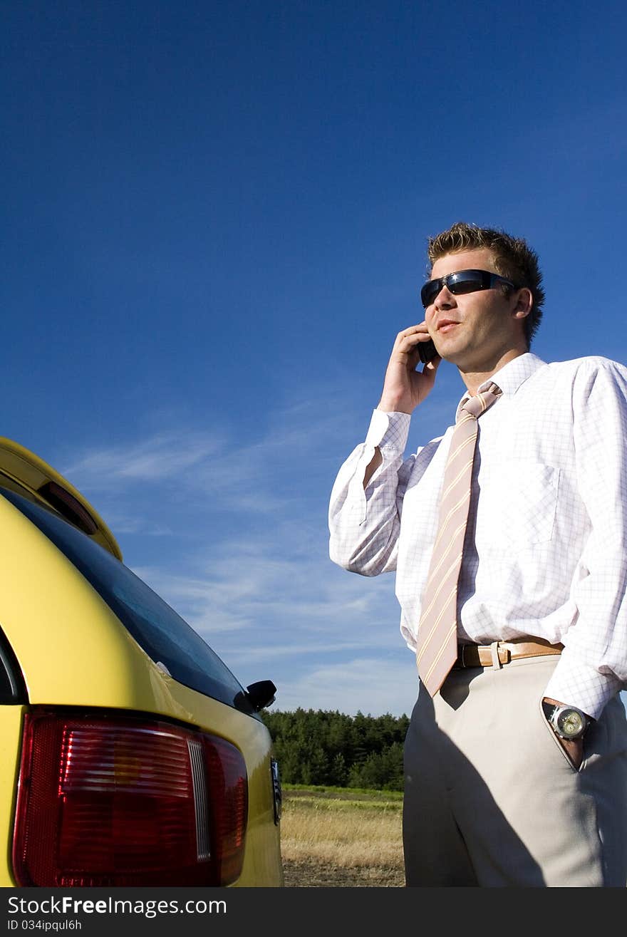 A businessman dressed in a smart suit standing on grass and talking on mobile phone. A businessman dressed in a smart suit standing on grass and talking on mobile phone.