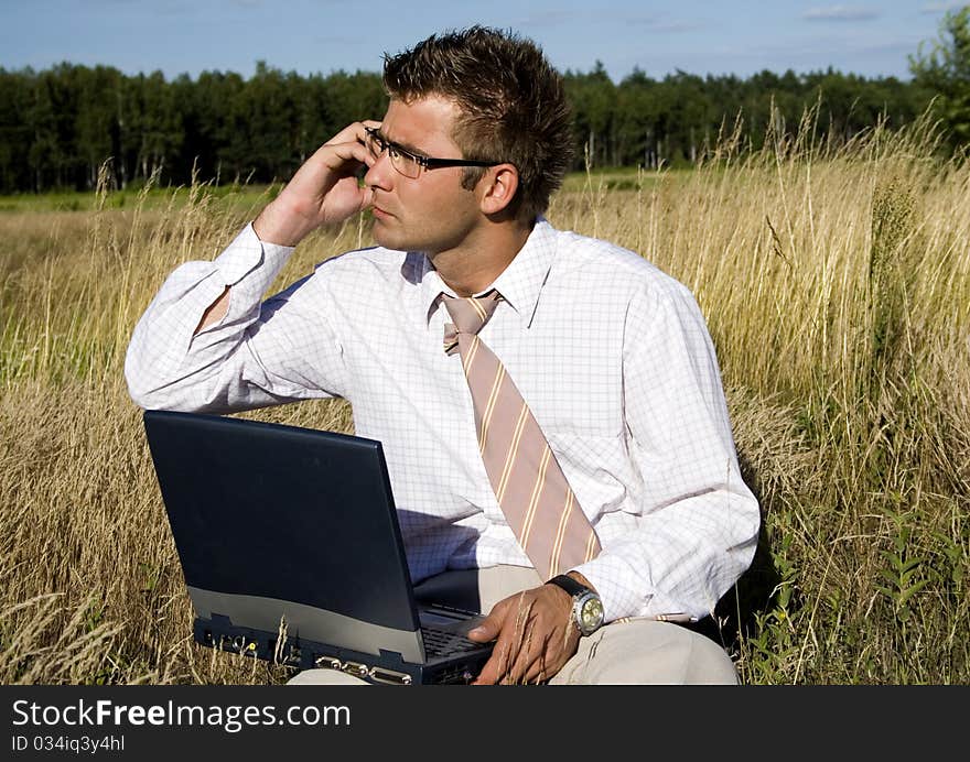 Elegant businessman working on his laptop in nature.