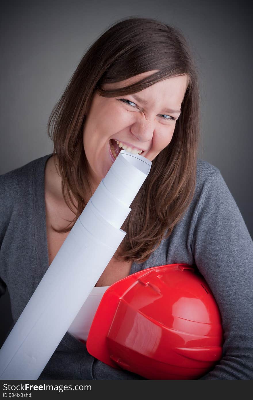 Portrait of young architect wearing red hardhat, eating plans