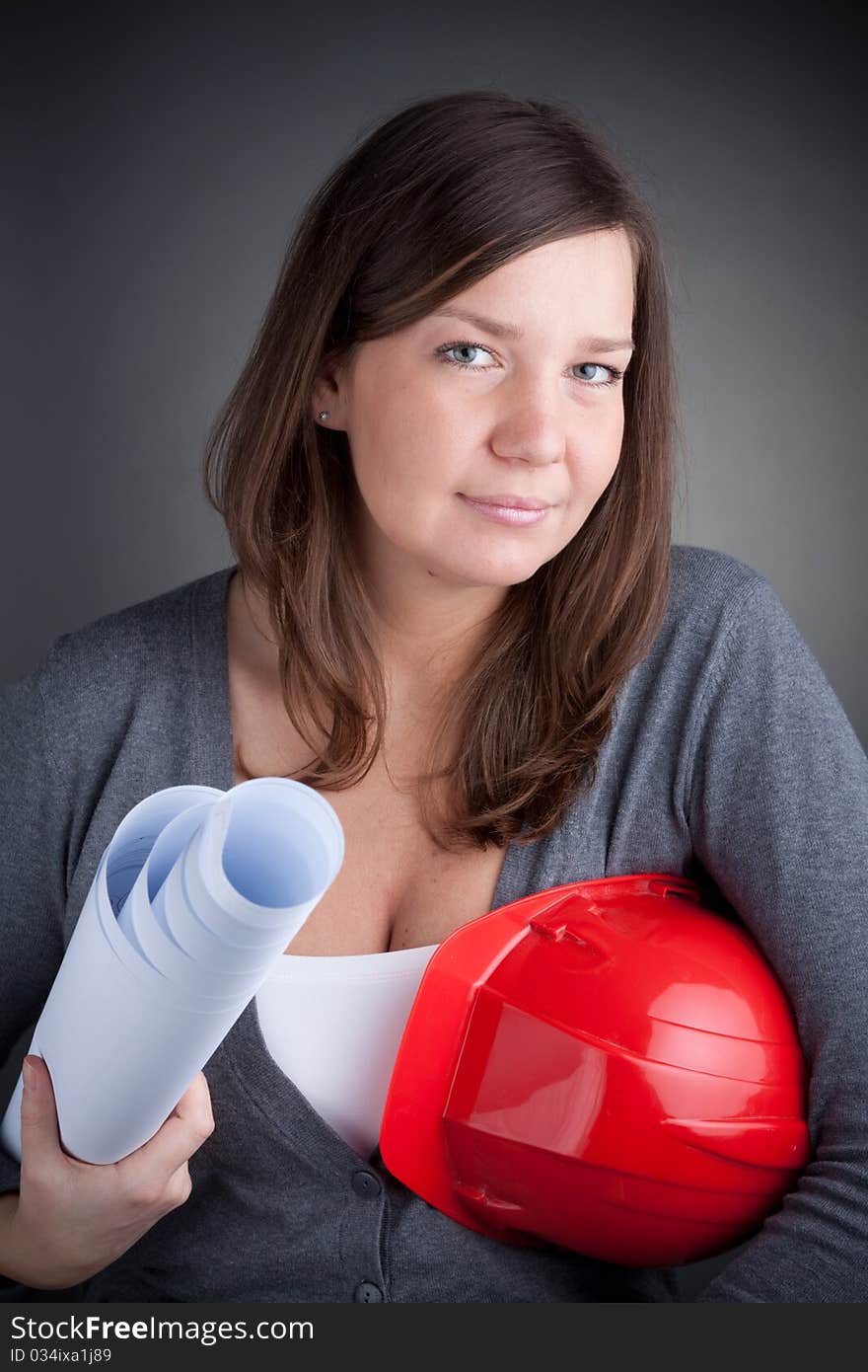 Portrait of young architect wearing red hardhat, looking at came