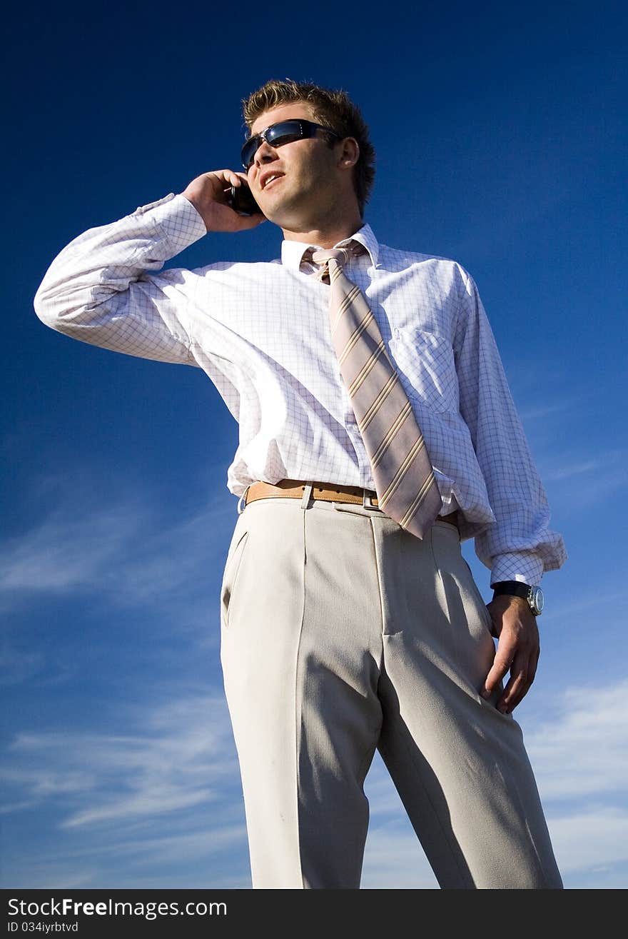 A businessman dressed in a smart suit standing on grass and talking on mobile phone. A businessman dressed in a smart suit standing on grass and talking on mobile phone.