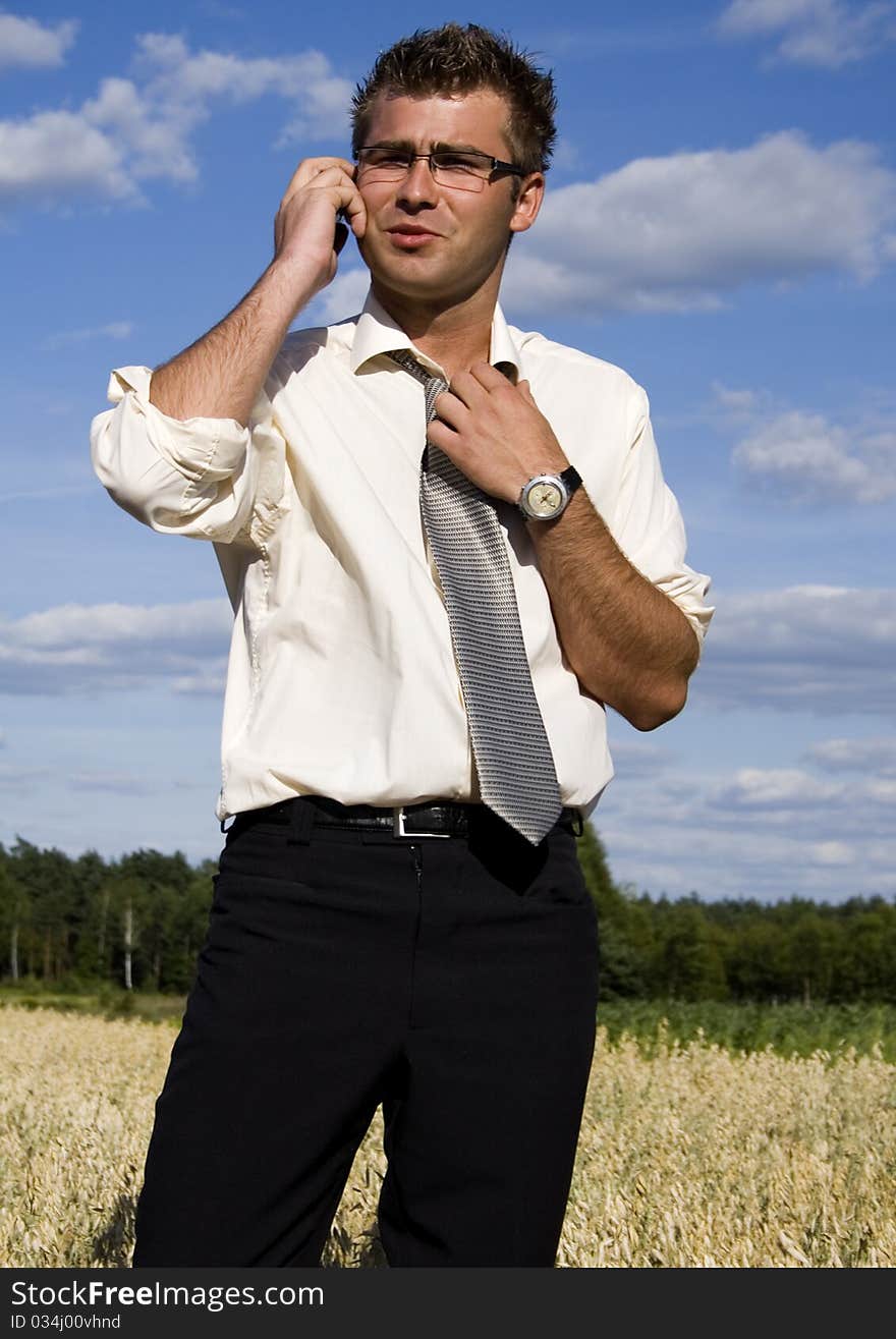 A businessman dressed in a smart suit standing on grass and talking on mobile phone. A businessman dressed in a smart suit standing on grass and talking on mobile phone.