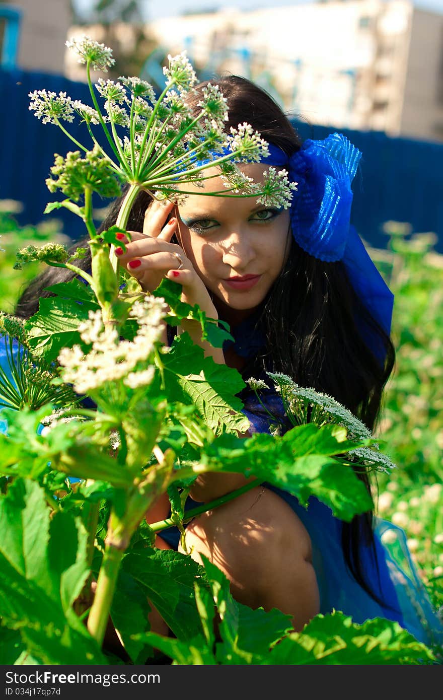 Beautiful girl with blue eyes and dark hair. Girl dressed in a blue cloth, like a dress. In her hair - burgundy flower. Beautiful girl with blue eyes and dark hair. Girl dressed in a blue cloth, like a dress. In her hair - burgundy flower