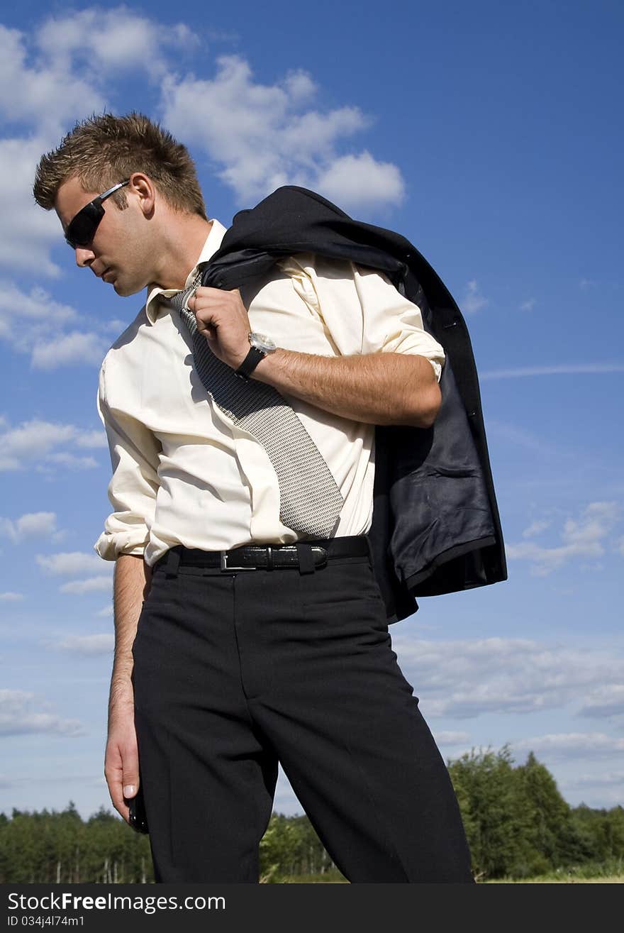 A businessman dressed in a smart suit standing on grass and talking on mobile phone. A businessman dressed in a smart suit standing on grass and talking on mobile phone.