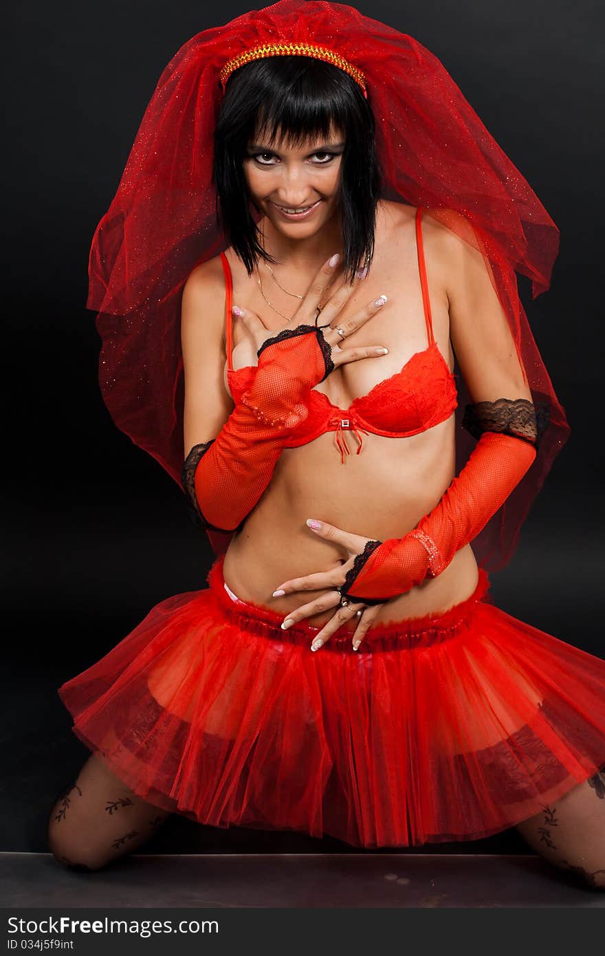 Beautiful dark-haired girl in a red wedding dress isolated on black background in studio. Beautiful dark-haired girl in a red wedding dress isolated on black background in studio