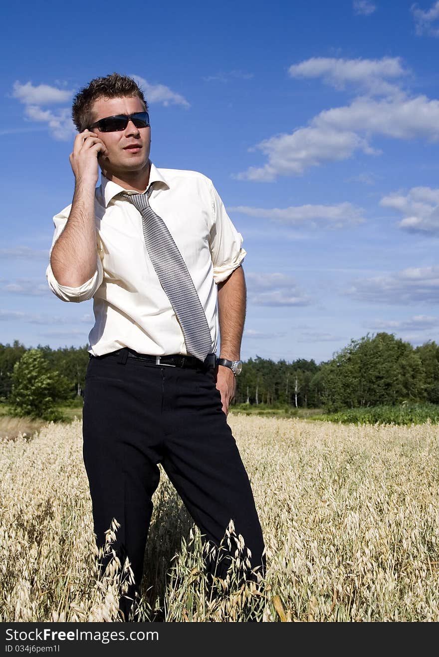 A businessman dressed in a smart suit standing on grass and talking on mobile phone. A businessman dressed in a smart suit standing on grass and talking on mobile phone.