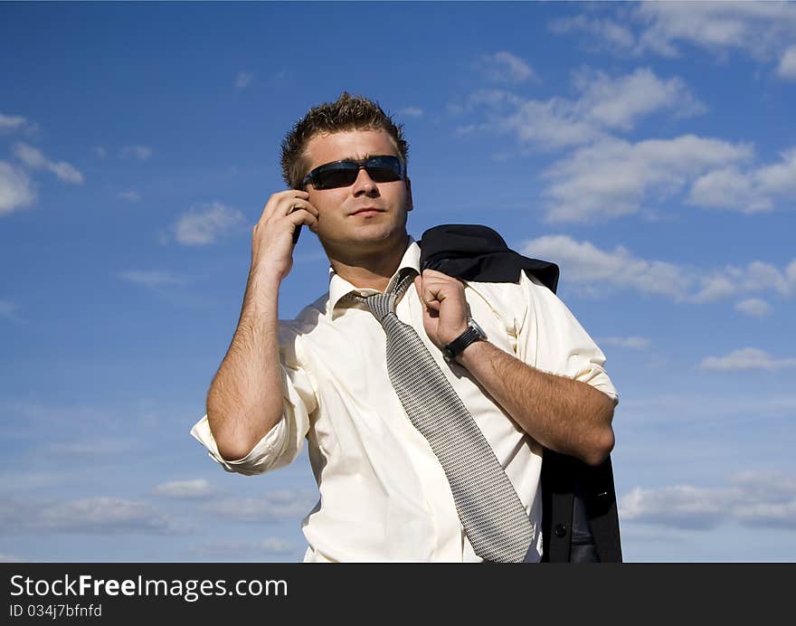 A businessman dressed in a smart suit standing on grass and talking on mobile phone. A businessman dressed in a smart suit standing on grass and talking on mobile phone.