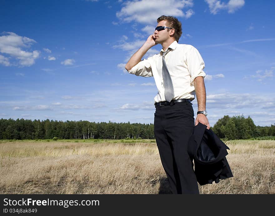 A businessman dressed in a smart suit standing on grass and talking on mobile phone. A businessman dressed in a smart suit standing on grass and talking on mobile phone.