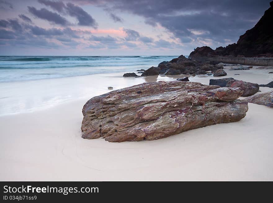 The beach at twilight with large rock in foreground