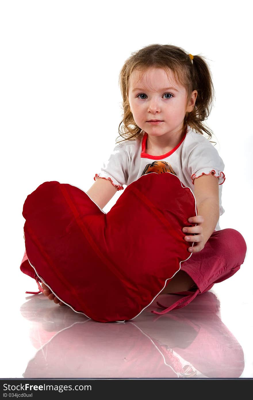 Beautiful girl sitting with heart shaped red pillow in red angel wings isolated on white