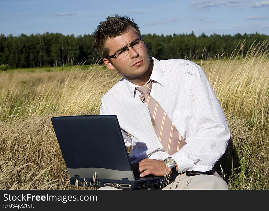 Elegant businessman working on his laptop in nature.