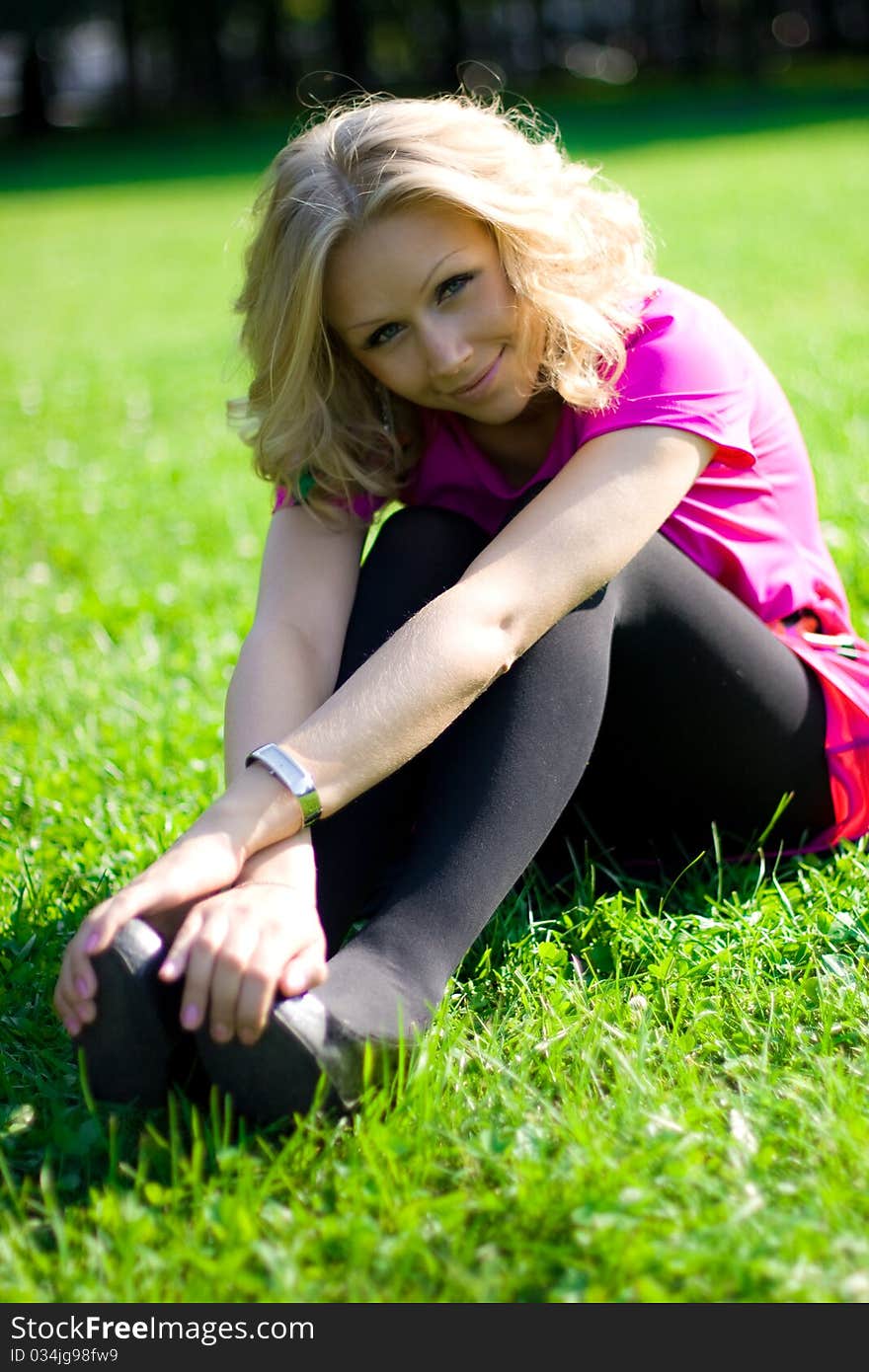 Young beautyful girl sitting on grass on a sunny day in a park. Young beautyful girl sitting on grass on a sunny day in a park