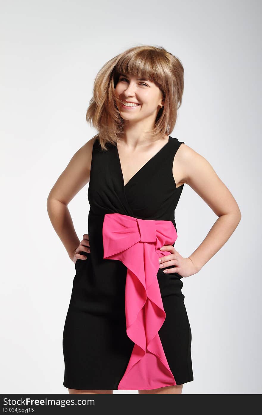 Beautiful smiling blonde girl in black dress with pink bow