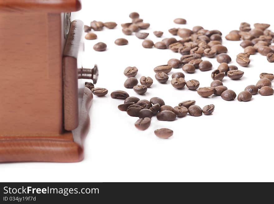 Coffee grinder made of a tree and metal and the roasted coffee beans on a white background. Coffee grinder made of a tree and metal and the roasted coffee beans on a white background