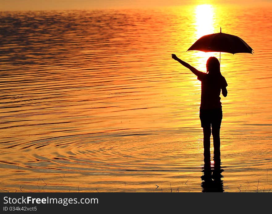 Silhouette of young woman wading in sea at sunset. Silhouette of young woman wading in sea at sunset