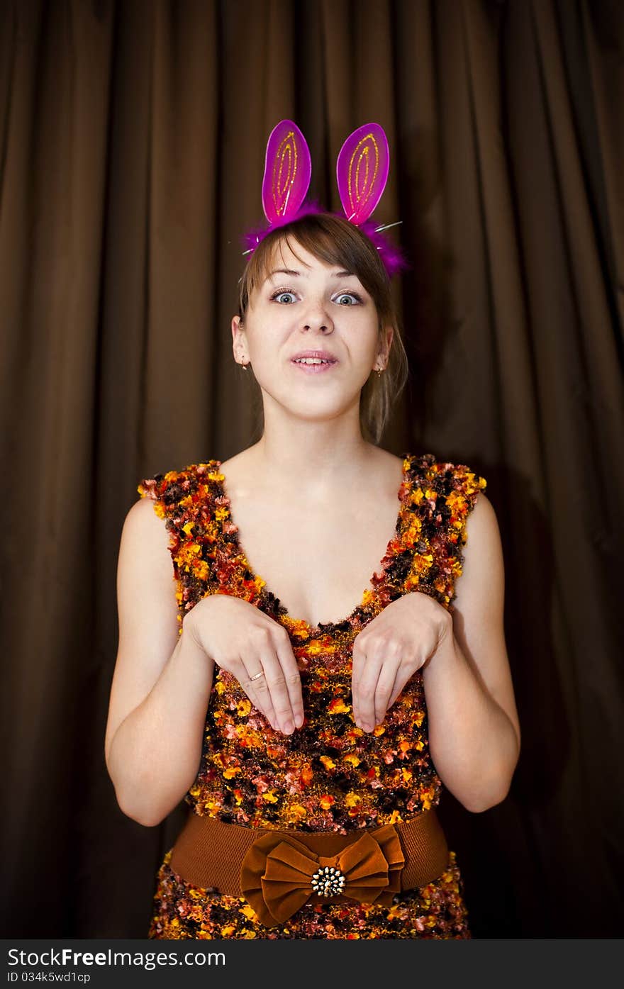 Woman with pink rabbit ears on brown background. Woman with pink rabbit ears on brown background