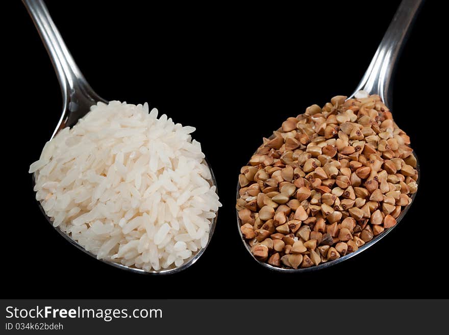 Rise and buckwheat on spoons with black isolated background