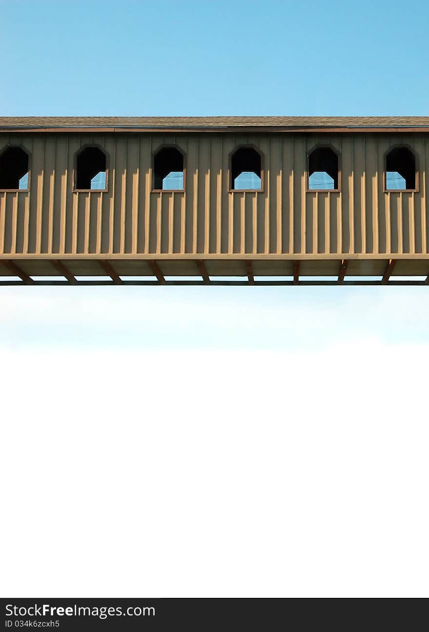 A metal covered bridge with blue sky above and white isolated background below.