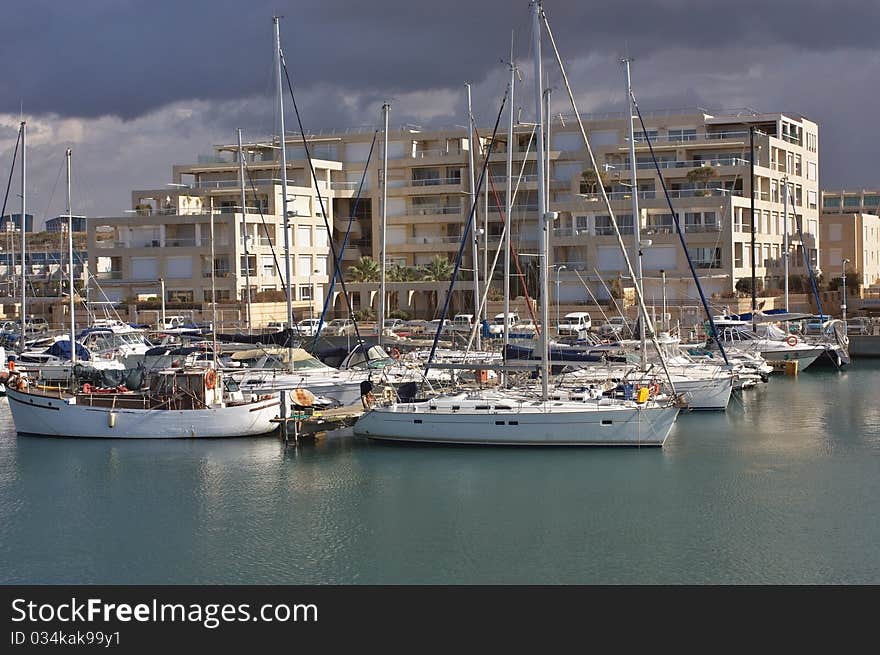 An image of Yachts anchored at the marina with stormy weather and cloudy sky