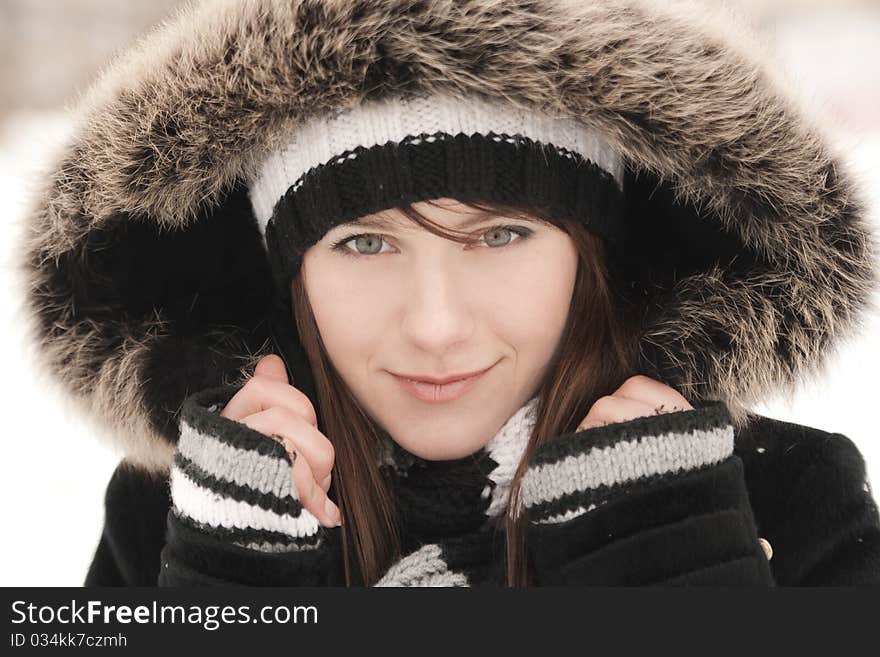 Young beautiful smiling woman in a striped hat, mittens and hood. Young beautiful smiling woman in a striped hat, mittens and hood