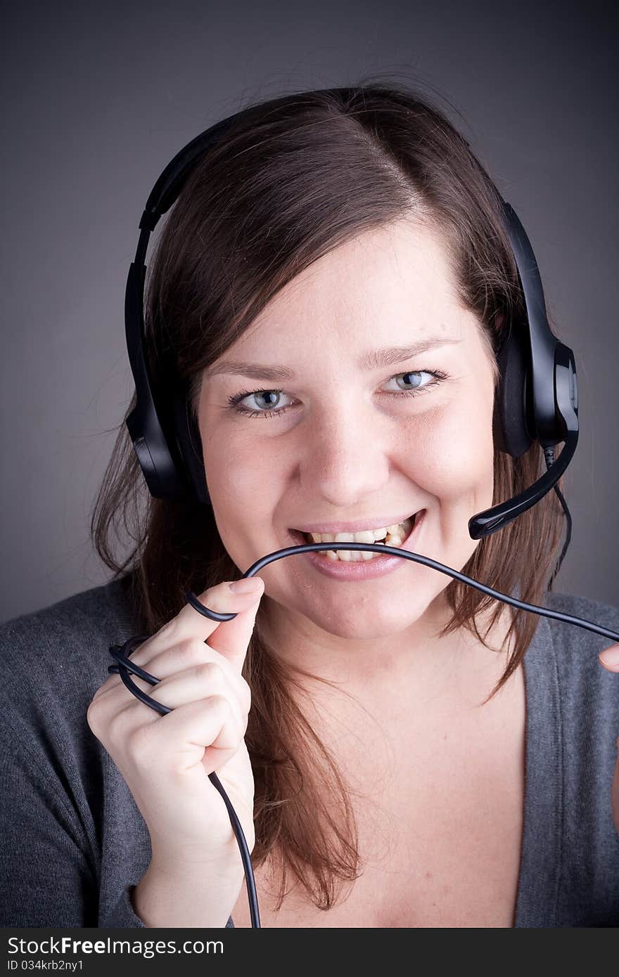 Studio picture from a young and beautiful callcenter agent, who eating the wire, grey background