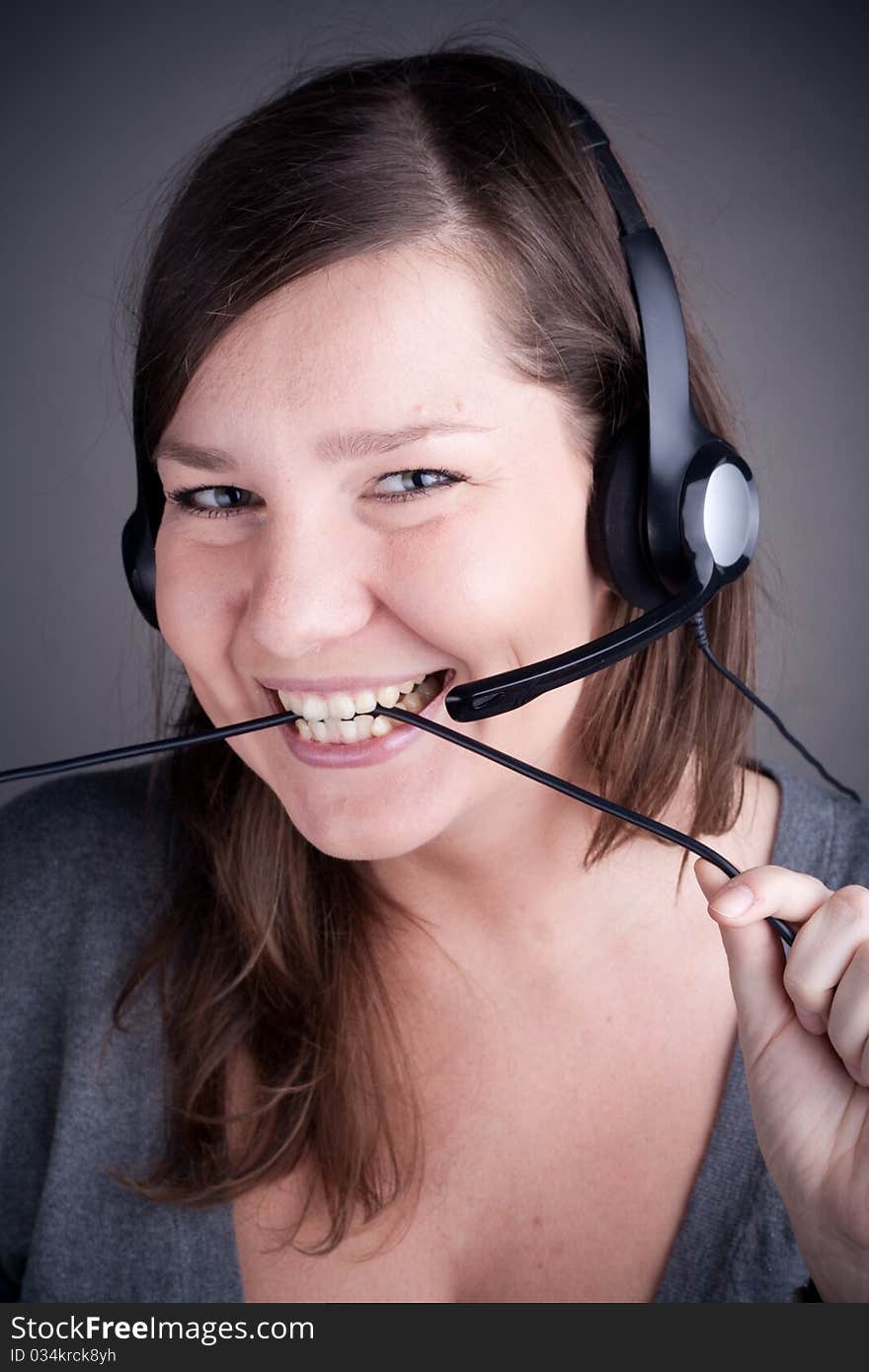 Studio picture from a young and beautiful callcenter agent, who eating the wire, grey background