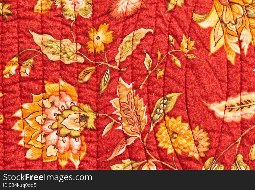 Quilted bedspread cover closeup with floral pattern and stitching